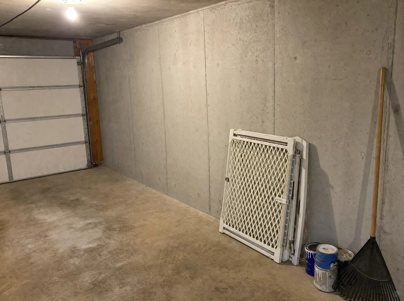 The folded baby gate leaning against the garage wall